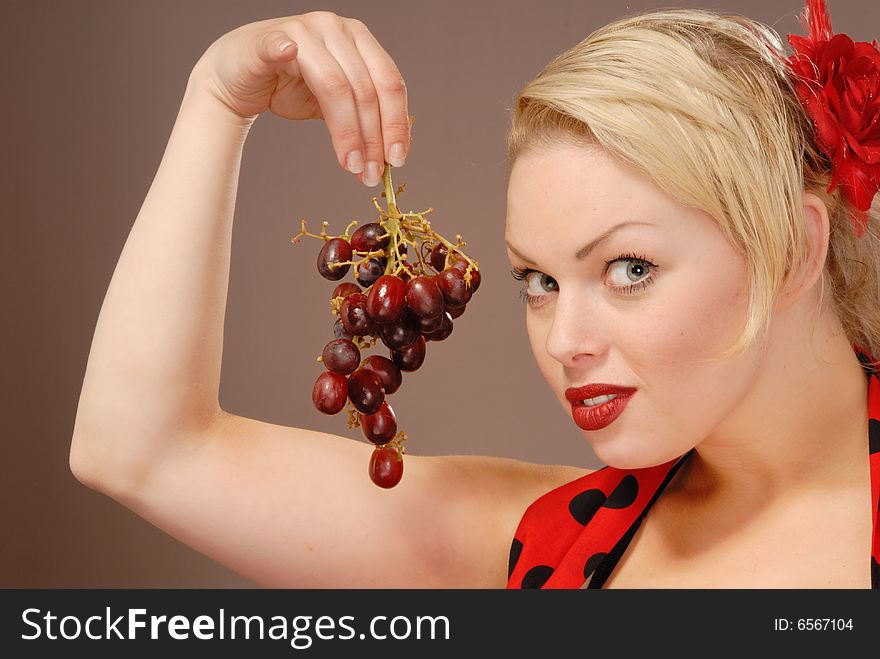 Pretty girl holding red grapes to tempt you. Pretty girl holding red grapes to tempt you