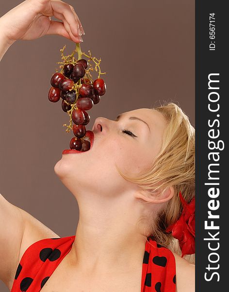 Pretty girl holding up red grapes and tasting them. Pretty girl holding up red grapes and tasting them