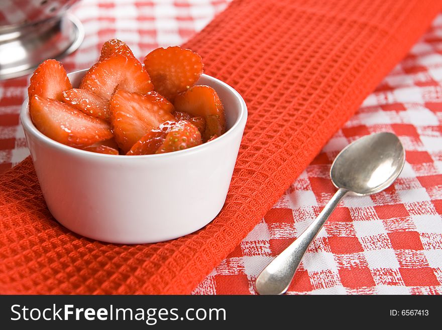 Fresh sliced strawberries in a white pot on a red cloth