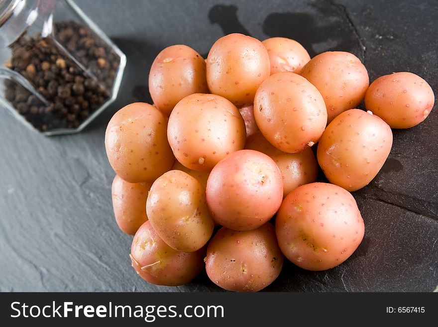 New potatoes with pepper on a slate background