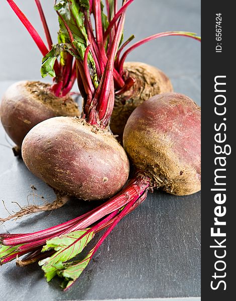 Four uncooked beetroots on a slate background
