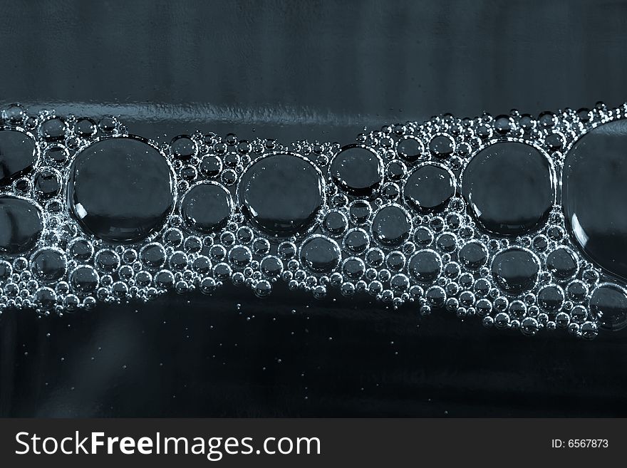 Steel blue water with bubbles under glass bottle, dark color