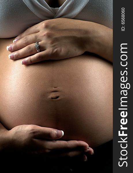 Young expectant mother sitting, holding her abdomen. Young expectant mother sitting, holding her abdomen