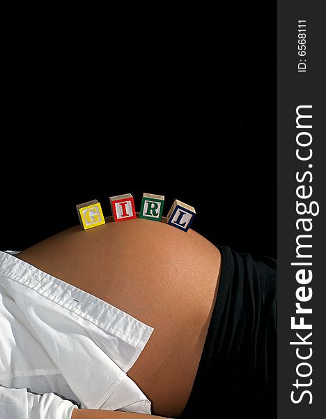Young mother reclining in front of a black background with GIRL spelled out with child's toy blocks. Young mother reclining in front of a black background with GIRL spelled out with child's toy blocks