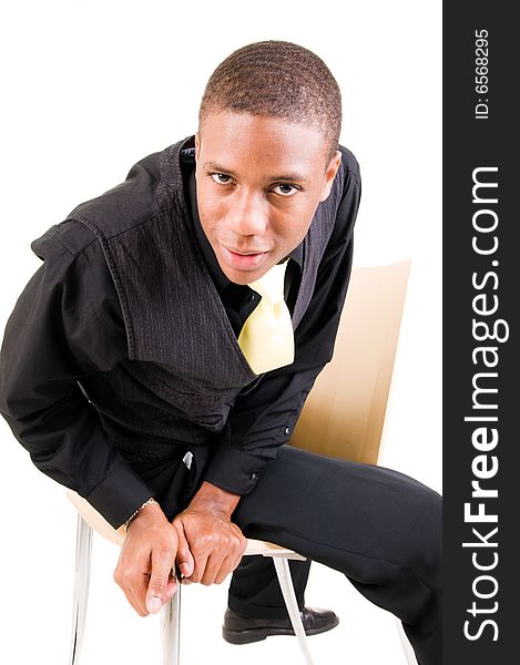 Young black man sits in chair and peers into the camera isolated on white background. Young black man sits in chair and peers into the camera isolated on white background