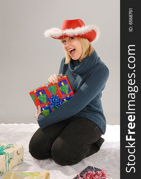 Excited cute blond girl wearing red hat holds Xmas gift. Excited cute blond girl wearing red hat holds Xmas gift