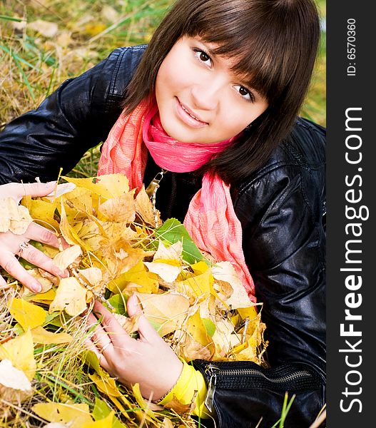 Pretty girl with yellow leaves in the park