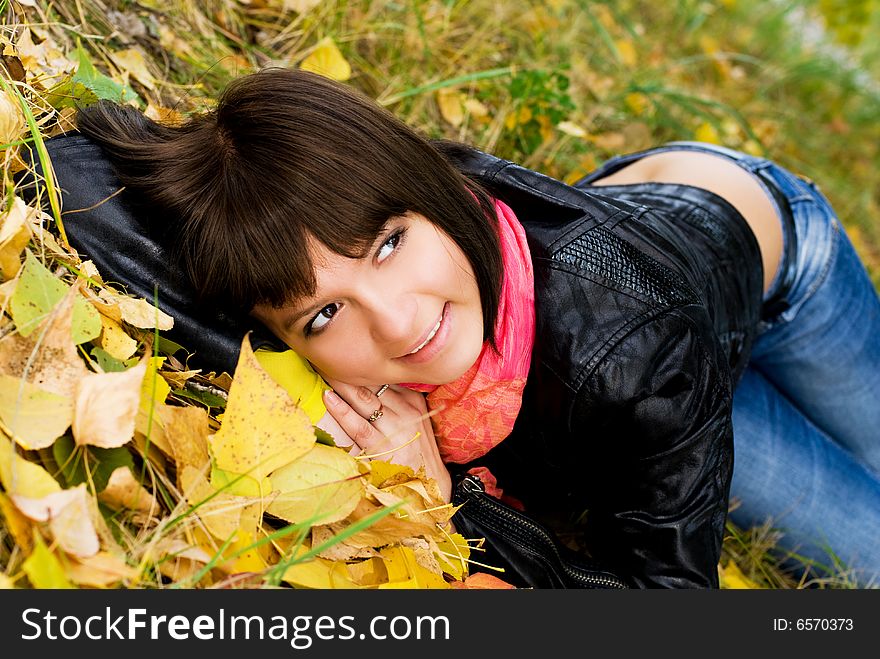 Happy cute girl on the grass covered with yellow leaves in the park. Happy cute girl on the grass covered with yellow leaves in the park