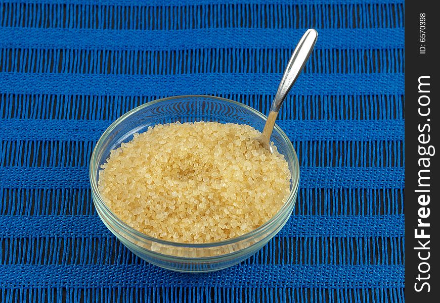 Raw sugar in clear glass bowl and spoon