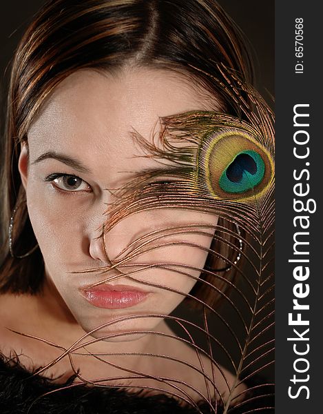 Portrait of female beauty holding peacok feather by her face. Portrait of female beauty holding peacok feather by her face