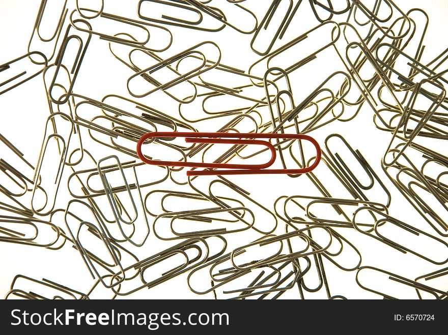 Big, red paper clip on the pile of small metal paper clips