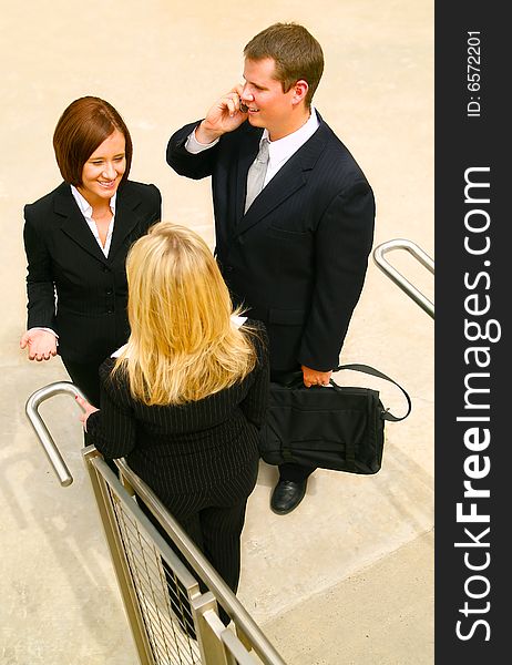 Business man talking on the phone and two other business women having a chat near stair. Business man talking on the phone and two other business women having a chat near stair