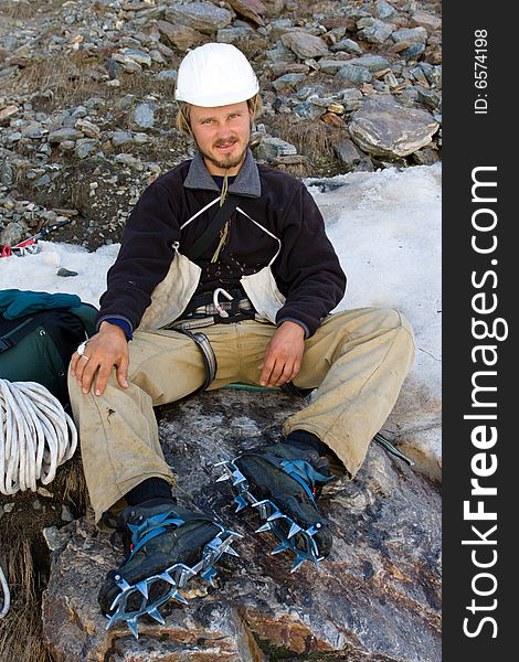 Climber in helmet and crampon sitting on stone. Climber in helmet and crampon sitting on stone