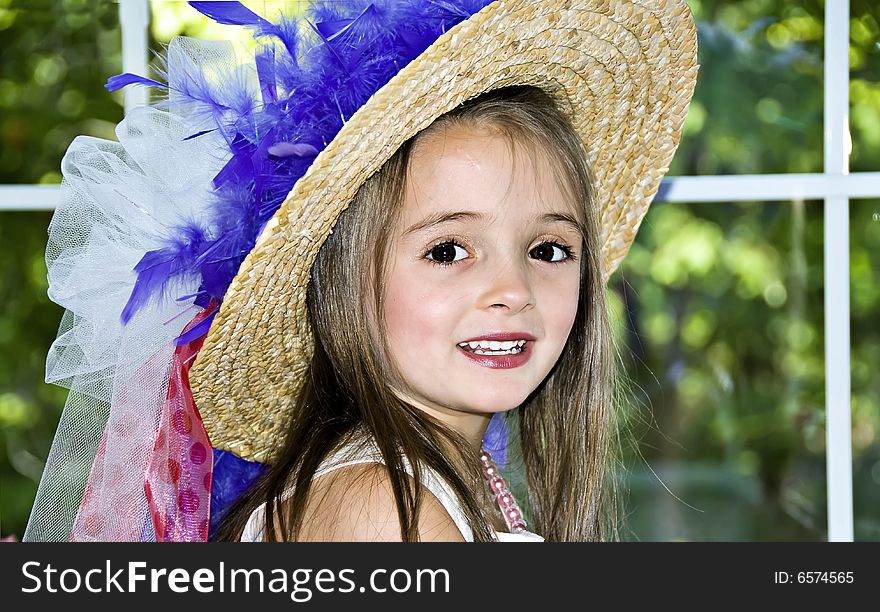 Little girl dressed up in a hat that has ribbons and feathers wrapped around it. Little girl dressed up in a hat that has ribbons and feathers wrapped around it.