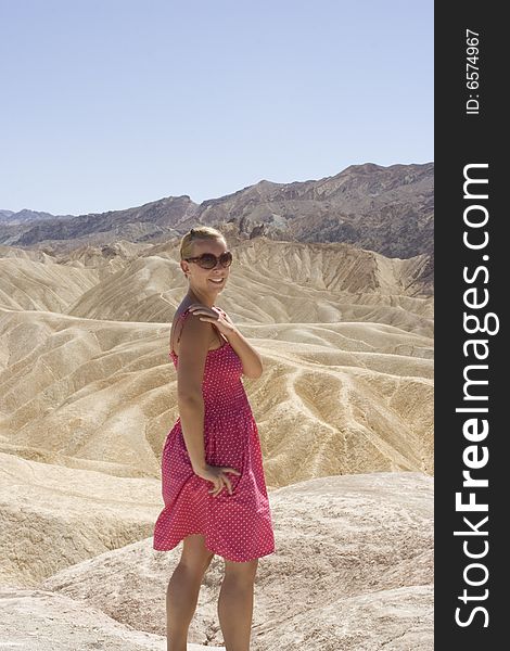 A lady wearing a pink dress posing before yellow mountains in death valley. A lady wearing a pink dress posing before yellow mountains in death valley