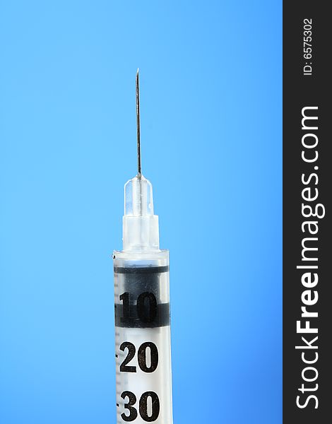 Vertical Hypodermic Needle against blue background. Vertical Hypodermic Needle against blue background