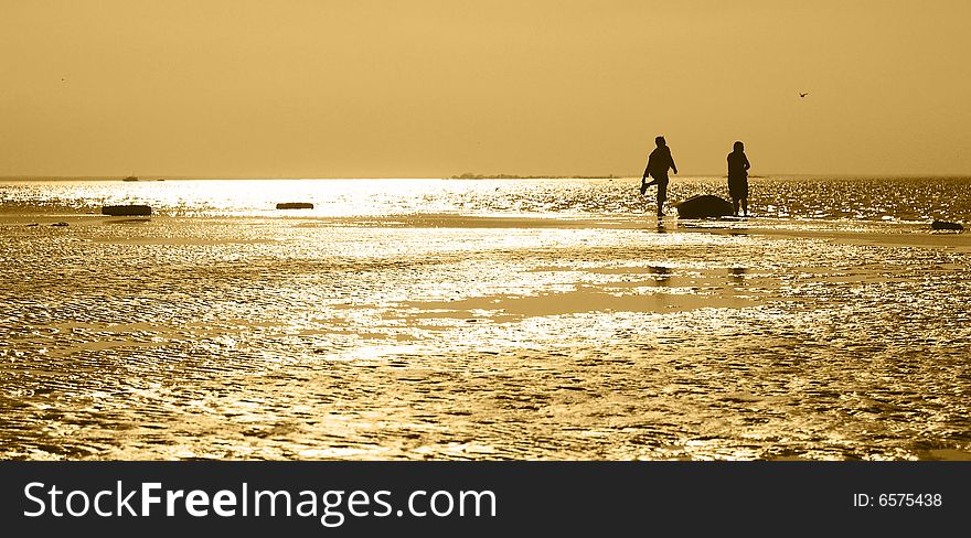 Two men with the boat on the shore during sunset. yellow toned.