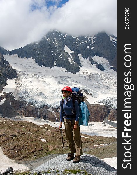 Backpacker girl in helmet standing on big stone