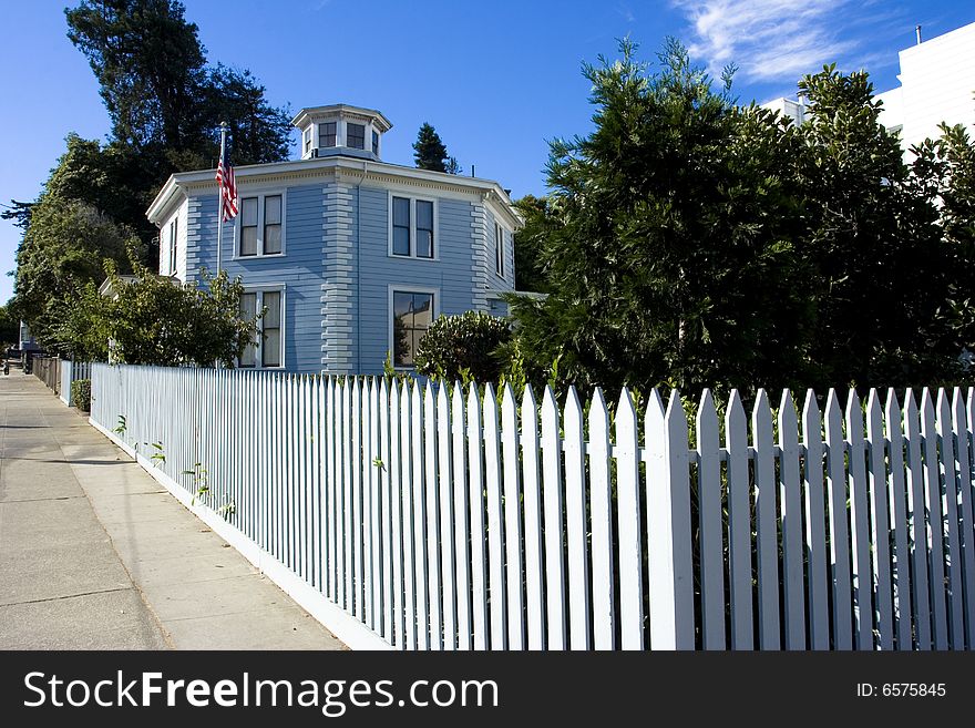 An american house with a fence surrounding it. An american house with a fence surrounding it