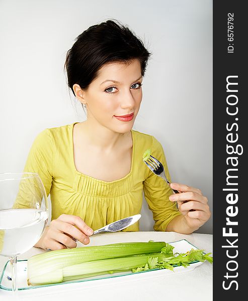 Young woman having her breakfast with water and celery