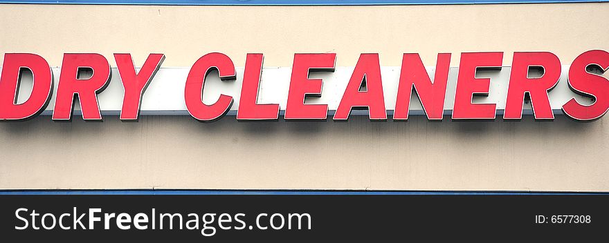 Photo of a dry cleaners sign during the day.