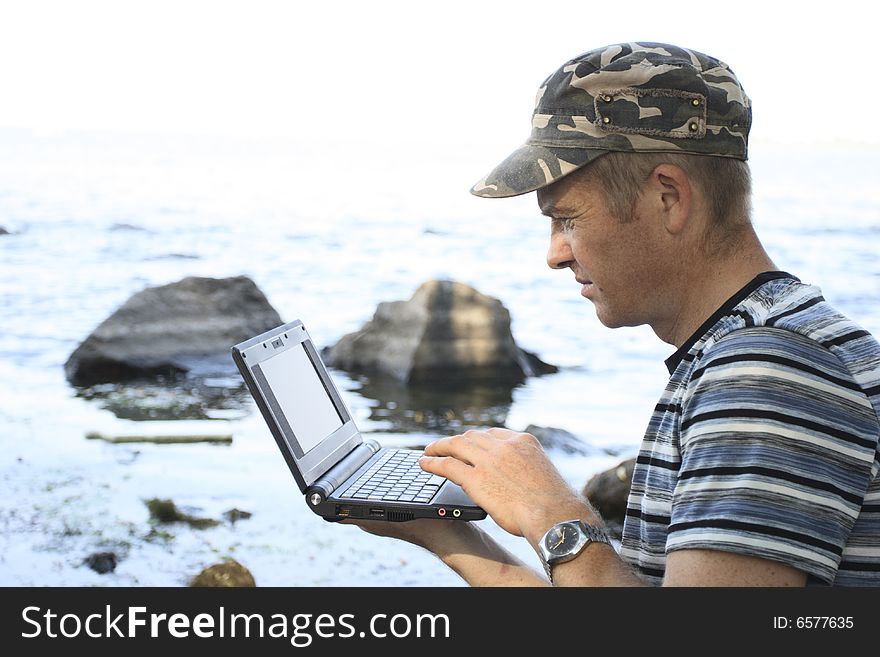 Man works at notebook sitting on stone