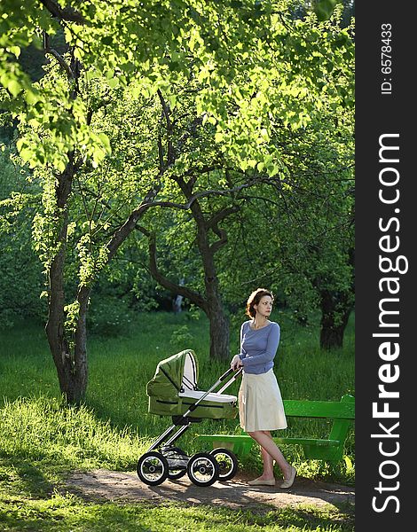 Mother with baby carriage in summer park. Mother with baby carriage in summer park