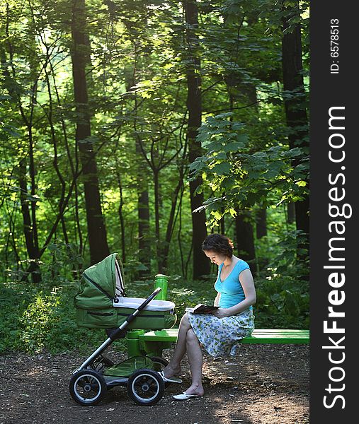 Mother with baby carriage in the summer park