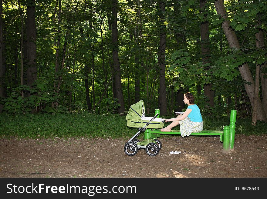 Mother with baby carriage in the summer park