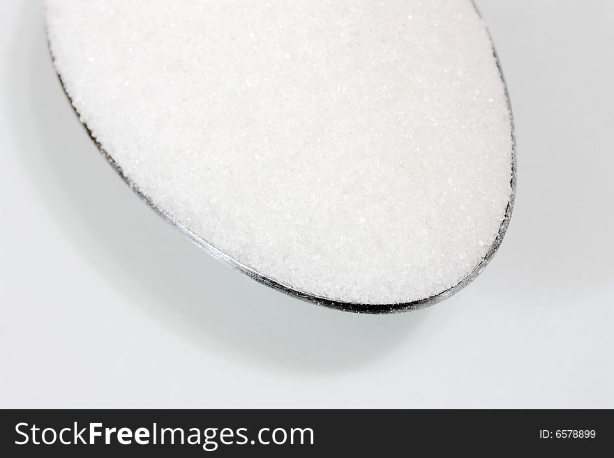 A macro shot of white sugar in a spoon (focus on the front area of the sugar). A macro shot of white sugar in a spoon (focus on the front area of the sugar)