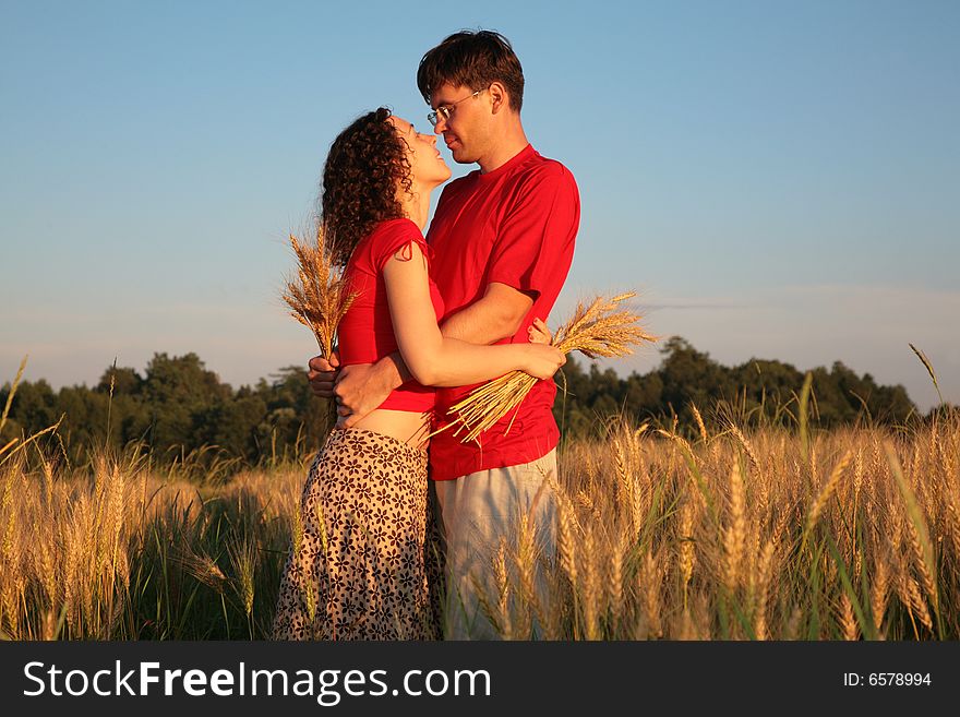 Romantic pair embraces on wheaten field