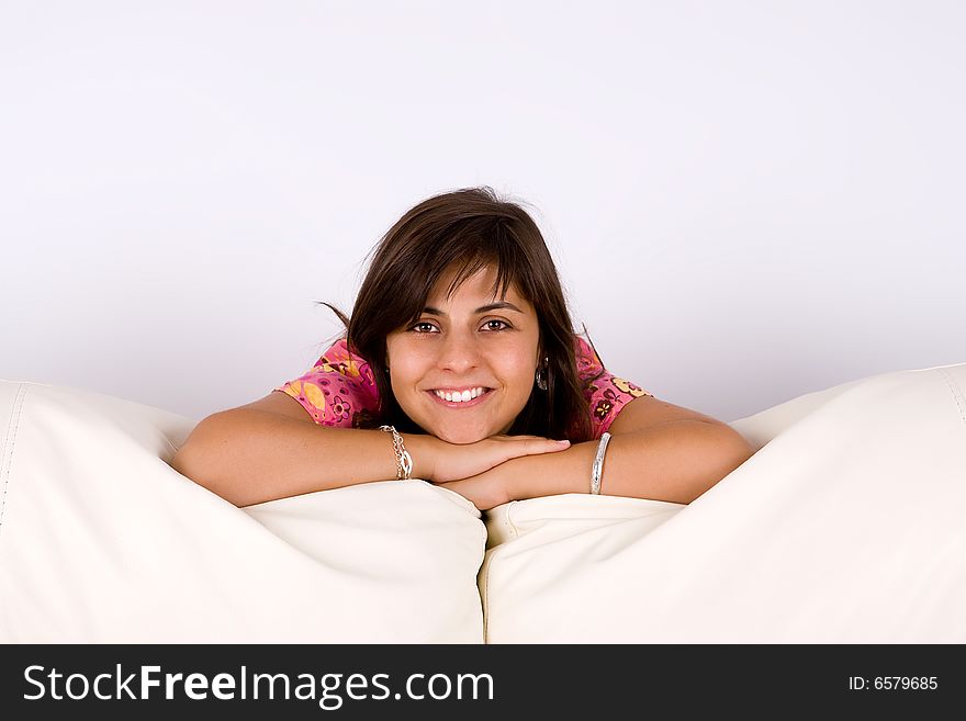 Beautiful young woman smiling bent over white sofa