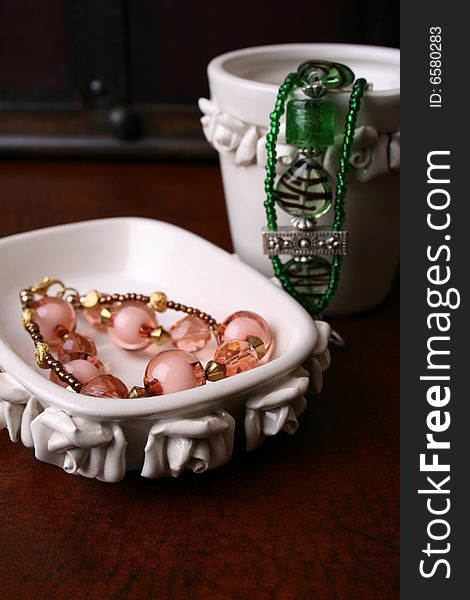 Orange and Green jewelery in a white ceramic bowl