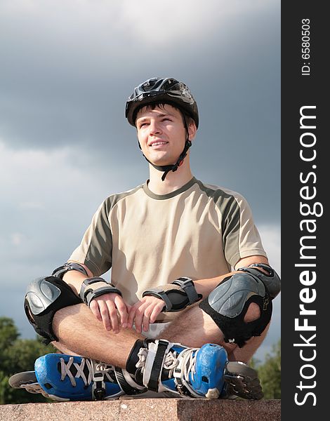 Boy on rollerblades sits with crossed legs in yoga pose on sky