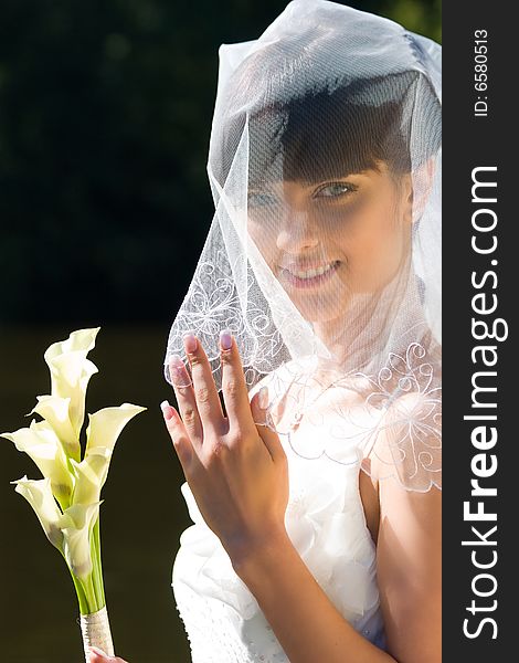 Smiling bride with bouquet under veil