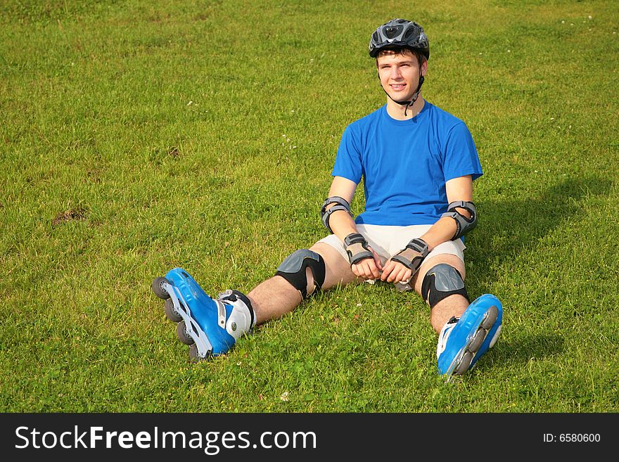 Guy In Rollerblades Sits On Grass