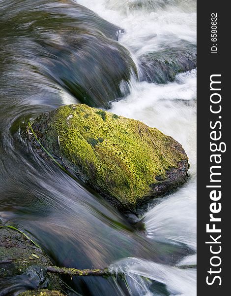 Stone covered with a moss in the falling rough river. Stone covered with a moss in the falling rough river