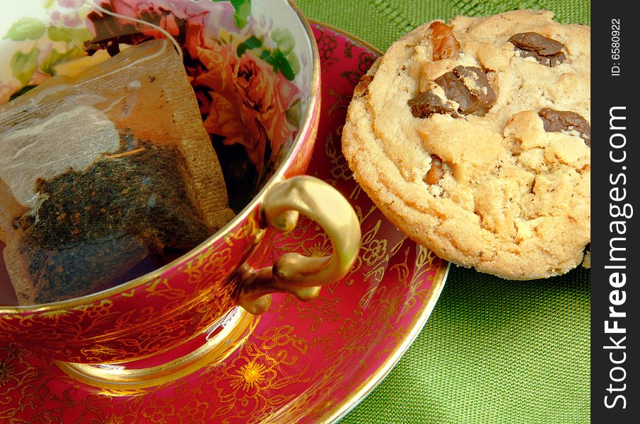 Tea in and antique cup with a chocolate chip cookie. Tea in and antique cup with a chocolate chip cookie.