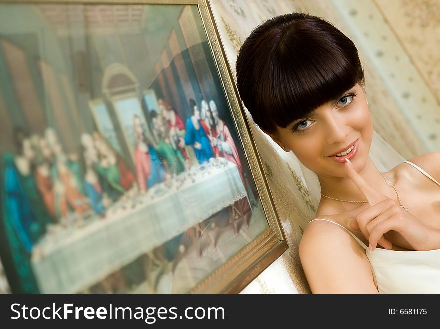 Mysterious bride is standing near picture with smile