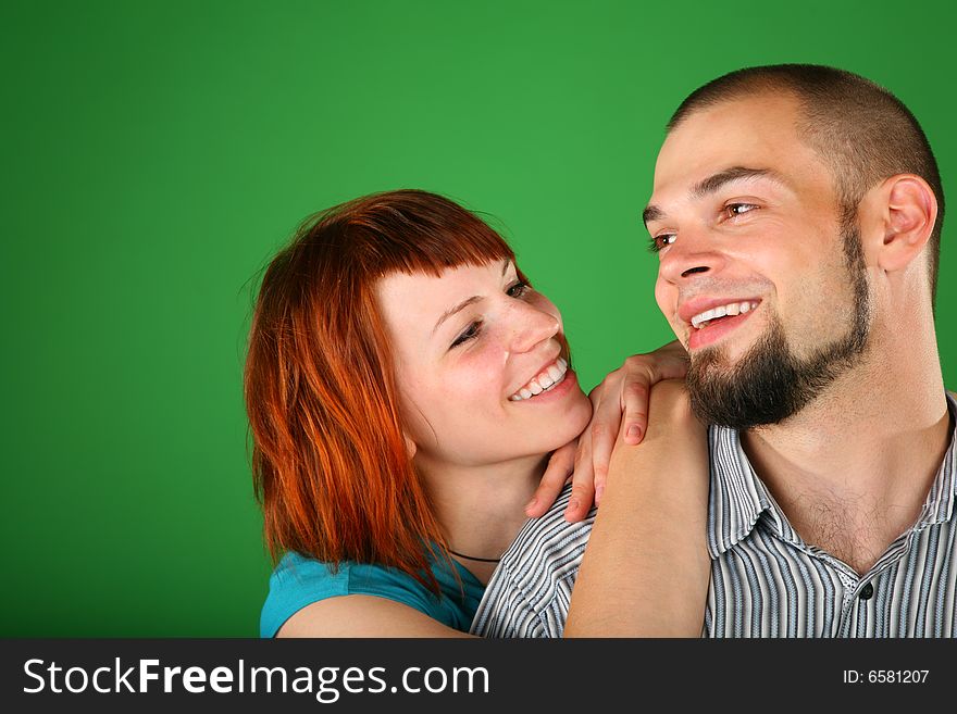 Girl with red hair embraces guy for shoulder on green