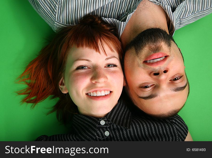 Girl with red hair and guy lie head to head on green
