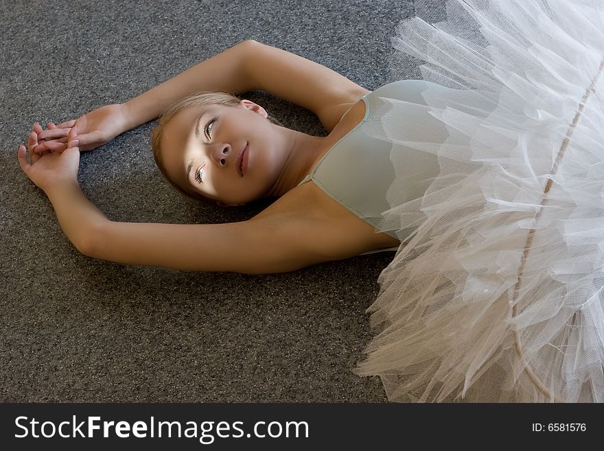 Smiling ballerina is relaxing on the floor. Smiling ballerina is relaxing on the floor