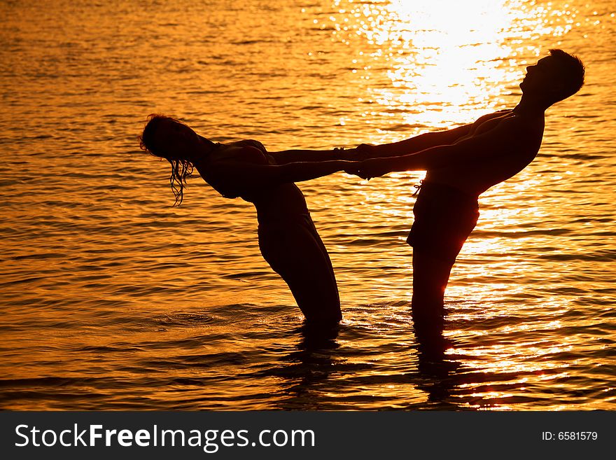 Silhouette Pair keeps for hands in sea on sunset