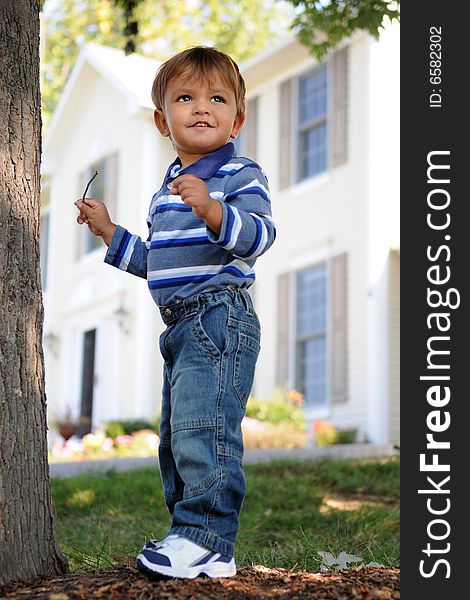 A happy 18-month-older playing in his front yard with his suburban house in the background. A happy 18-month-older playing in his front yard with his suburban house in the background.