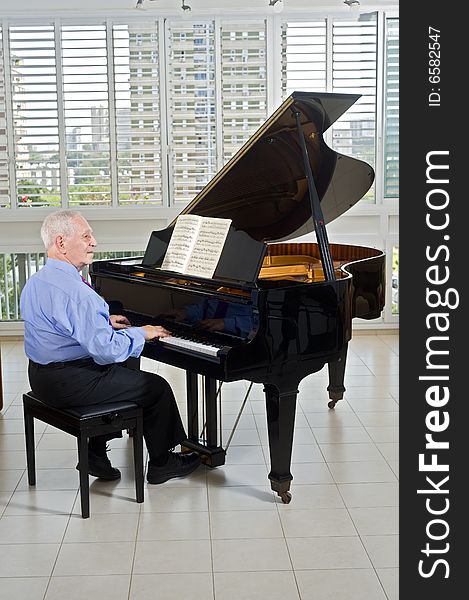 Senior man playing on a grand piano at home. Senior man playing on a grand piano at home
