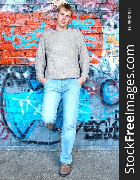 Young stylish man with blonde hair stand near graffiti brick wall. Young stylish man with blonde hair stand near graffiti brick wall.