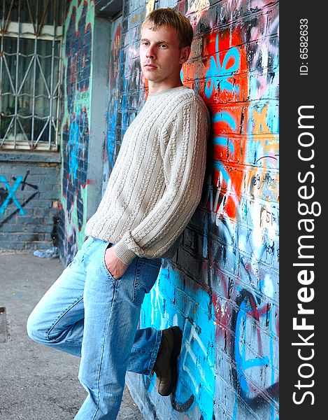 Young Stylish Man Stand Near Graffiti Brick Wall.