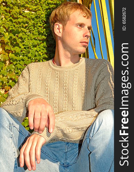 Young stylish man sit near overgrown wall.