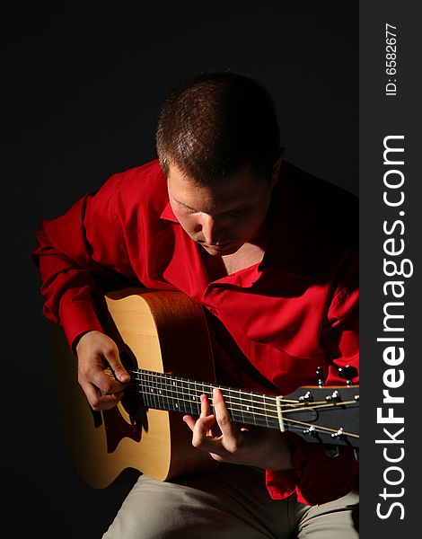 Guitarist in red shirt on dark