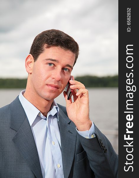 Portrait of the man near pond, which speaks on  cell phone. Portrait of the man near pond, which speaks on  cell phone